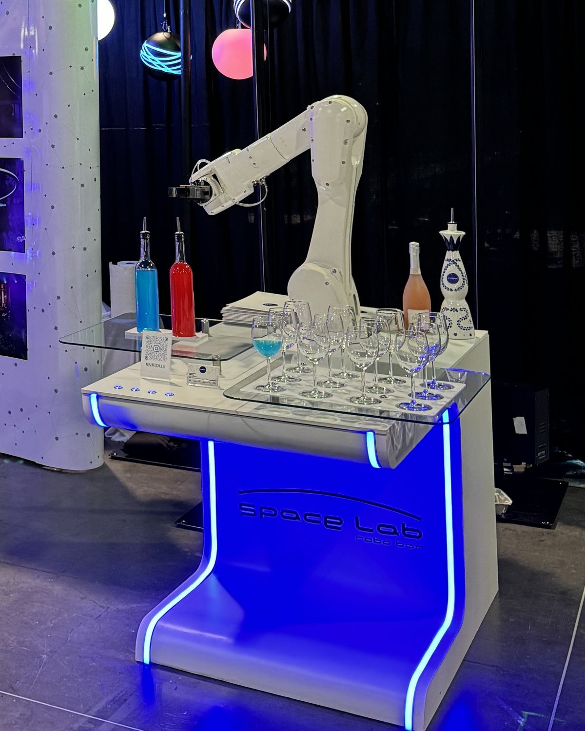 RoboBar robotic bartender arm over the glowing Space Lab bar with bottles and glasses at a Los Angeles show