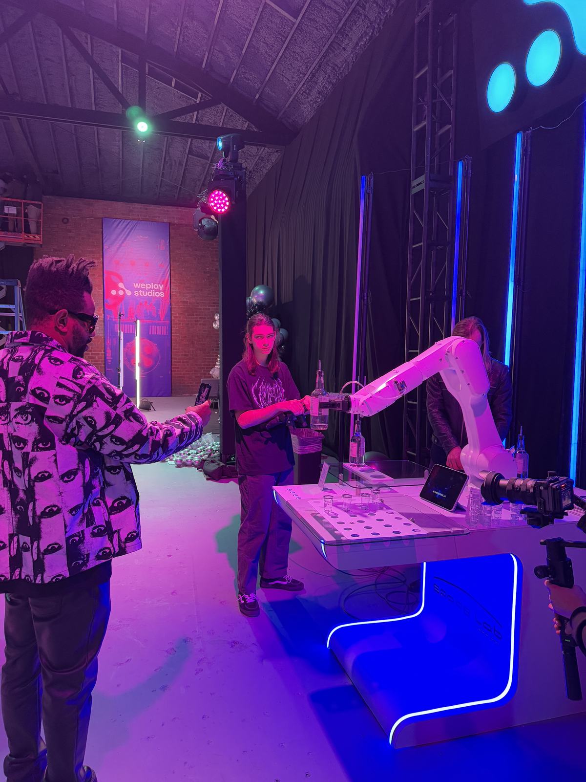Guests toasting beside the RoboBar robotic bartender at the Weplay Studios grand opening in Los Angeles