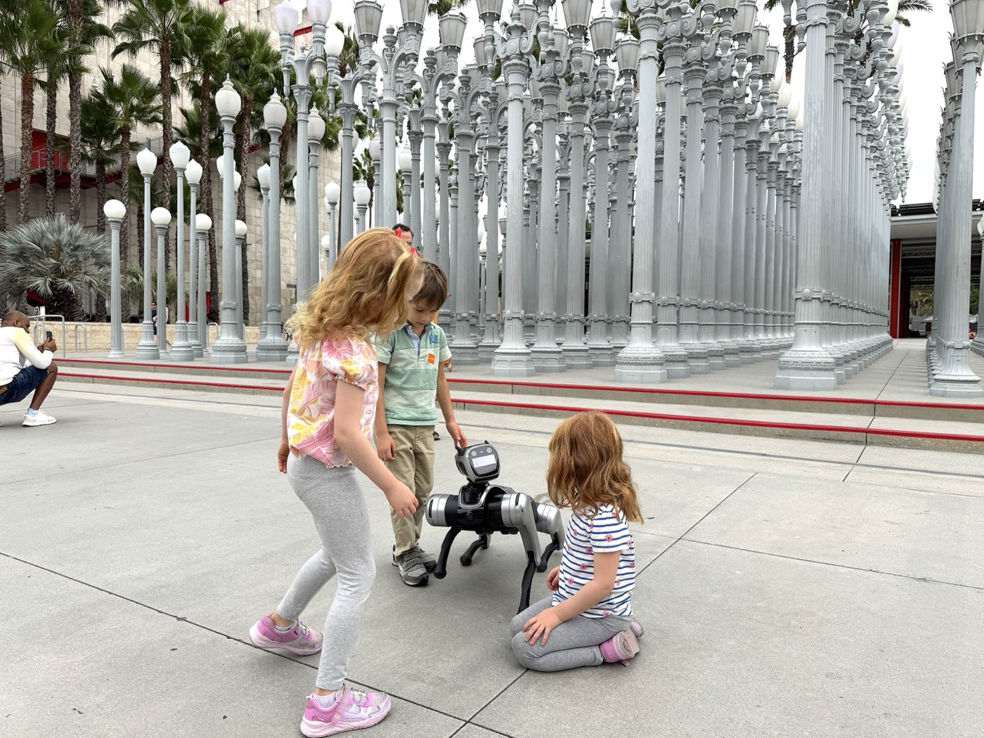 Young guests playing with the RoboDog robot dog at LACMA Urban Light in Los Angeles